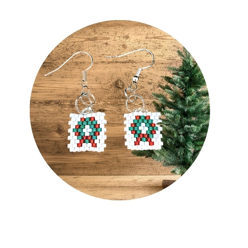 seed bead green holiday wreath earrings on wood background with a Christmas tree to the right side.