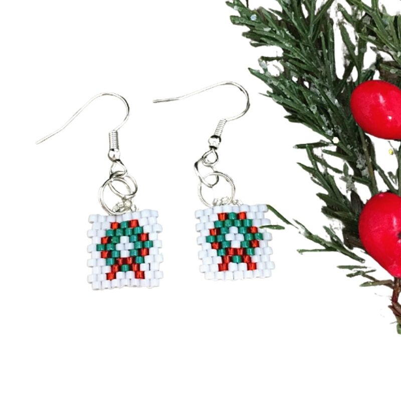 seed bead holly wreath earrings with a Christmas sprig next to them.
