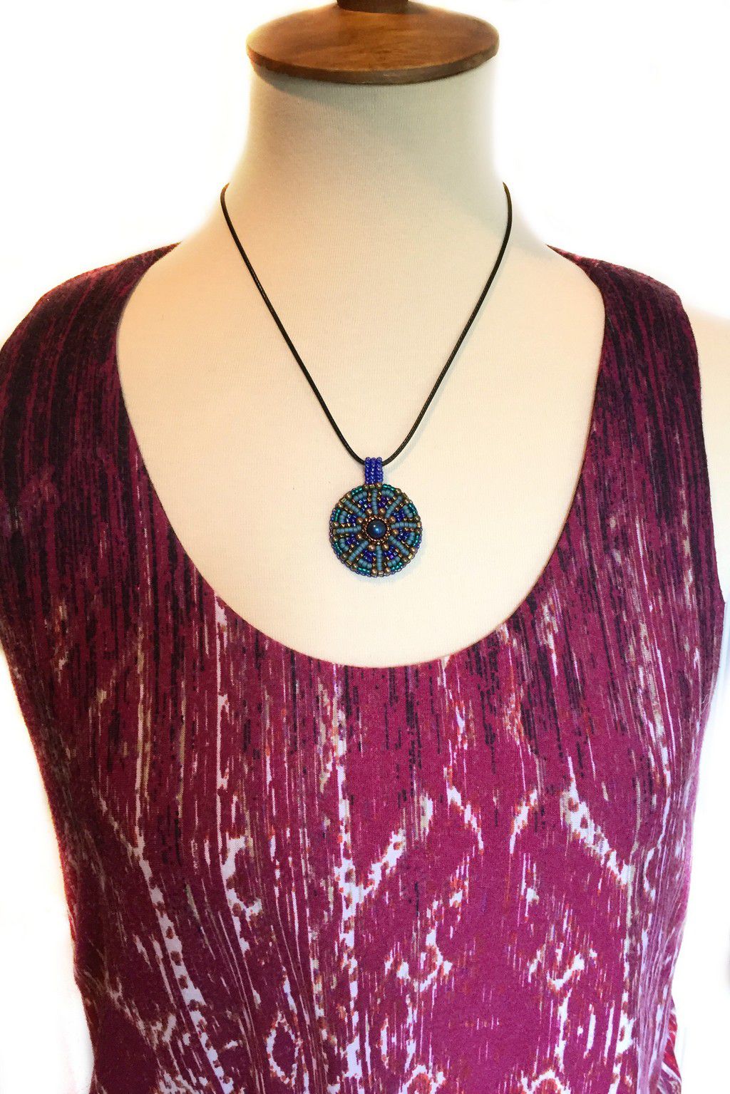 Model wearing seed beaded mandala pendant necklace in blue and green.
