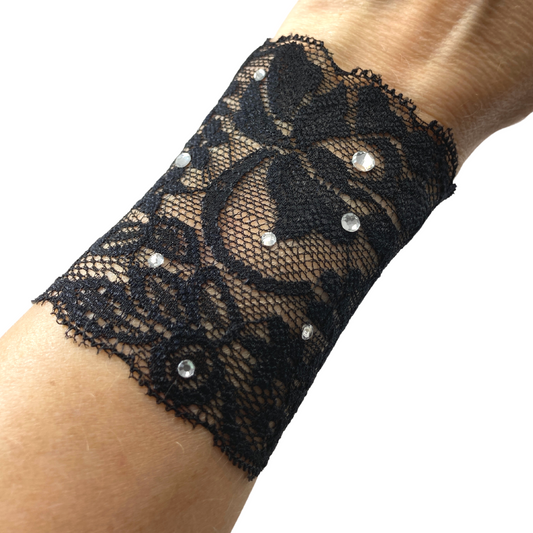 A black lace cuff bracelet with crystals modeled on wrist.