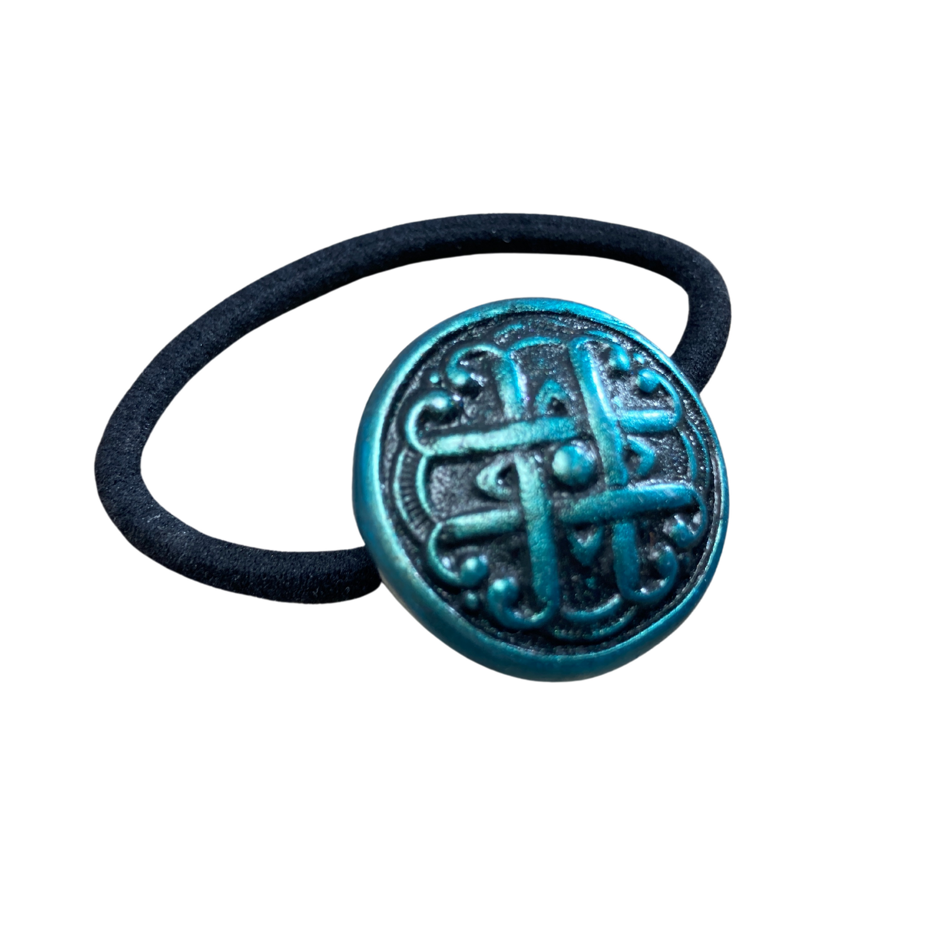 A close-up of a hair tie with a Celtic love knot design in green and black.