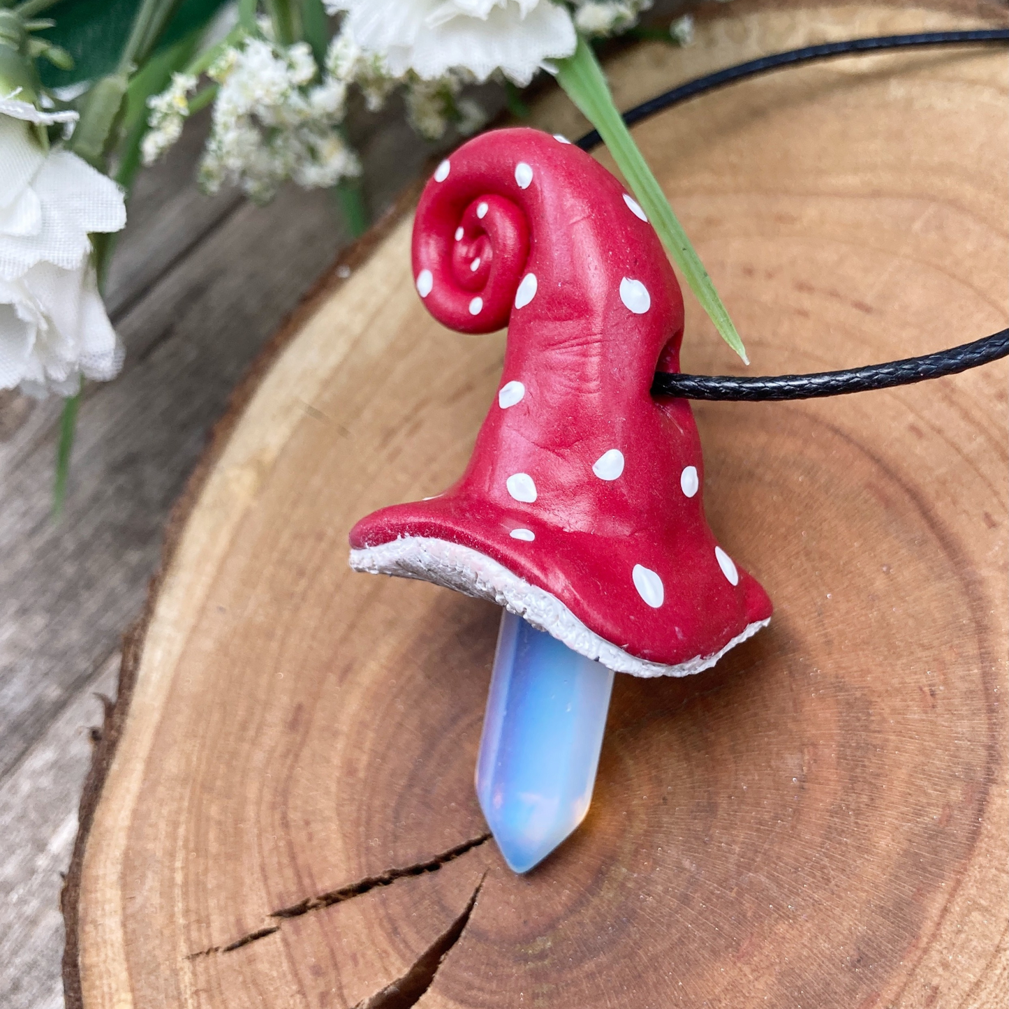 Side view of white spotted mushroom hat necklace with Opalite crystal point