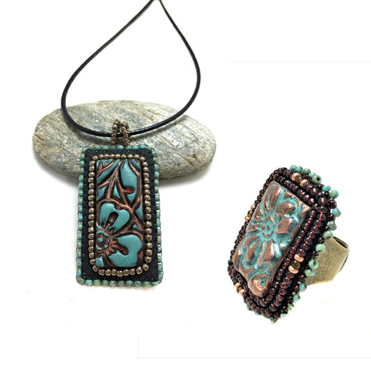A rectangle Patina Flower beaded Necklace and Ring Set. Necklace is resting on a pebble.