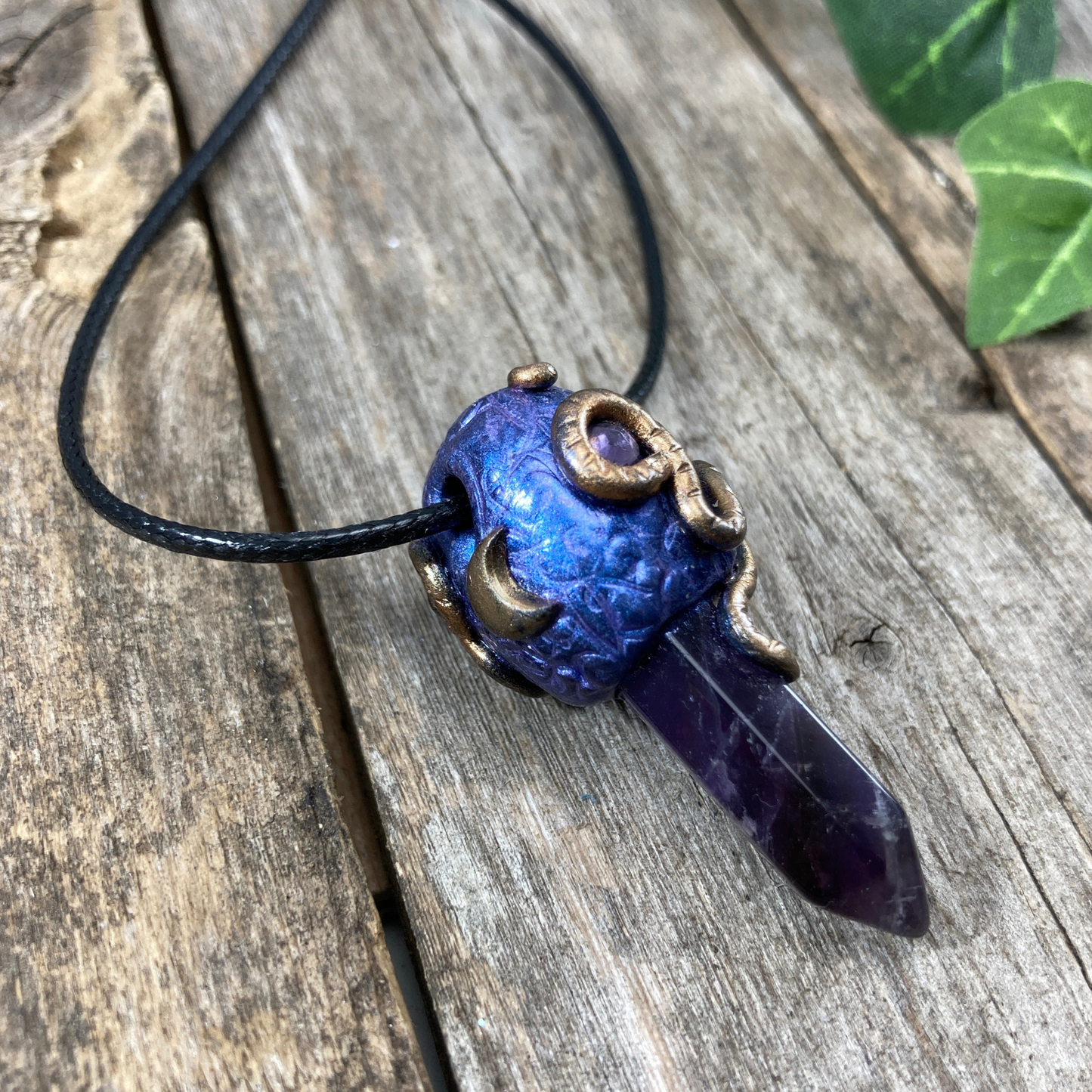 An Amethyst Crystal point necklace with purple polymer clay bail with snake design