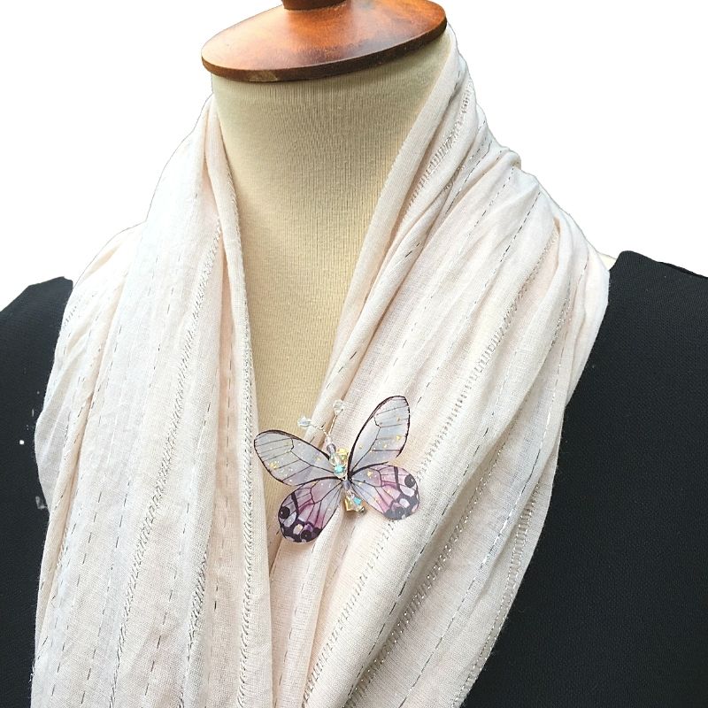A model wearing a purple butterfly brooch on shawl.