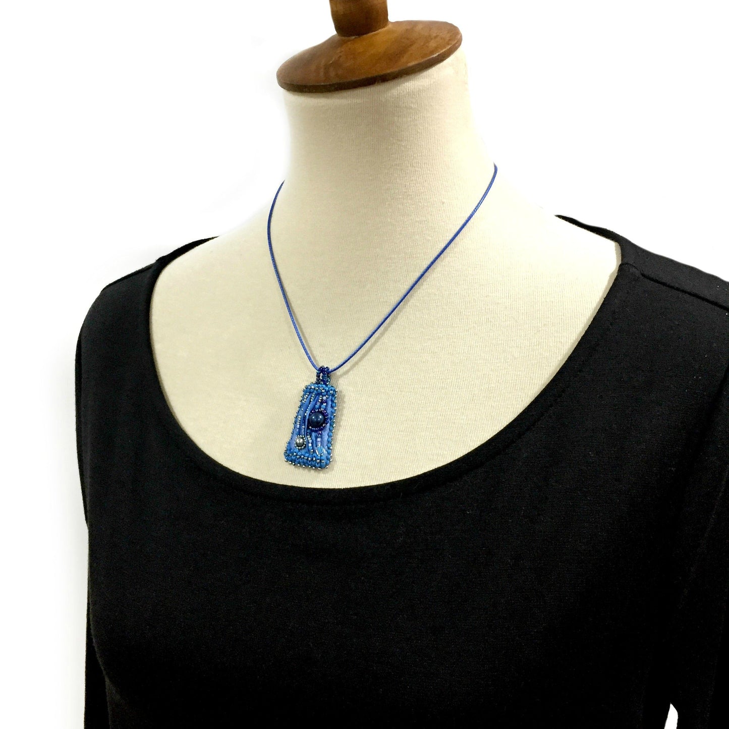 Model wearing small blue silk beaded pendant necklace.