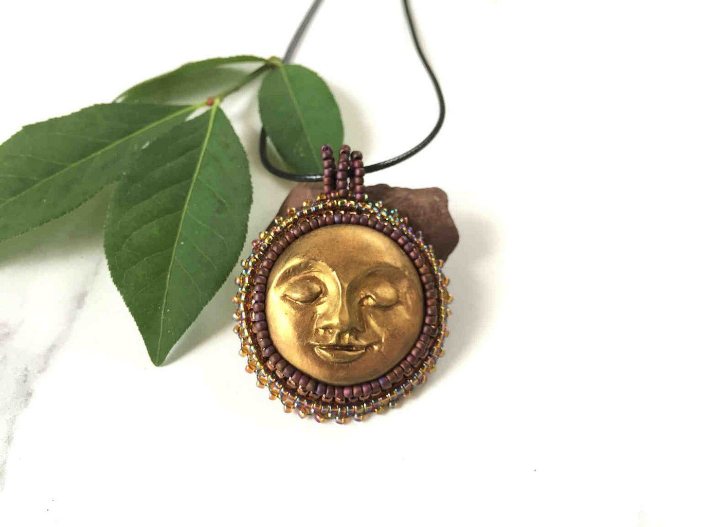 sun face round pendant in gold with burgandy and iradescent beaded bezel