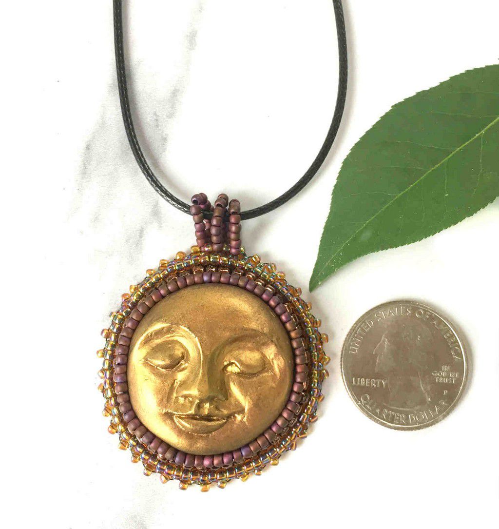 sun face round pendant in gold with burgandy and iradescent beaded bezel