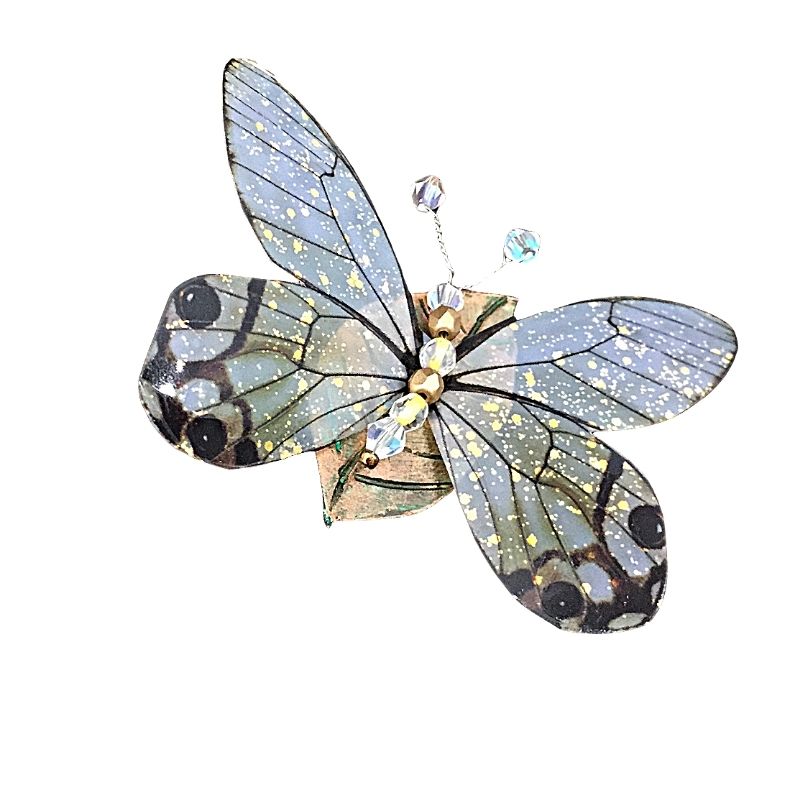 Yellow and clear winged butterfly pin with crystal antenna and abdomen on a leaf.
