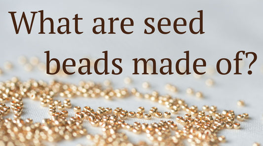 gold seed beads spread out on a table top. Title "What are seed beads made of?"