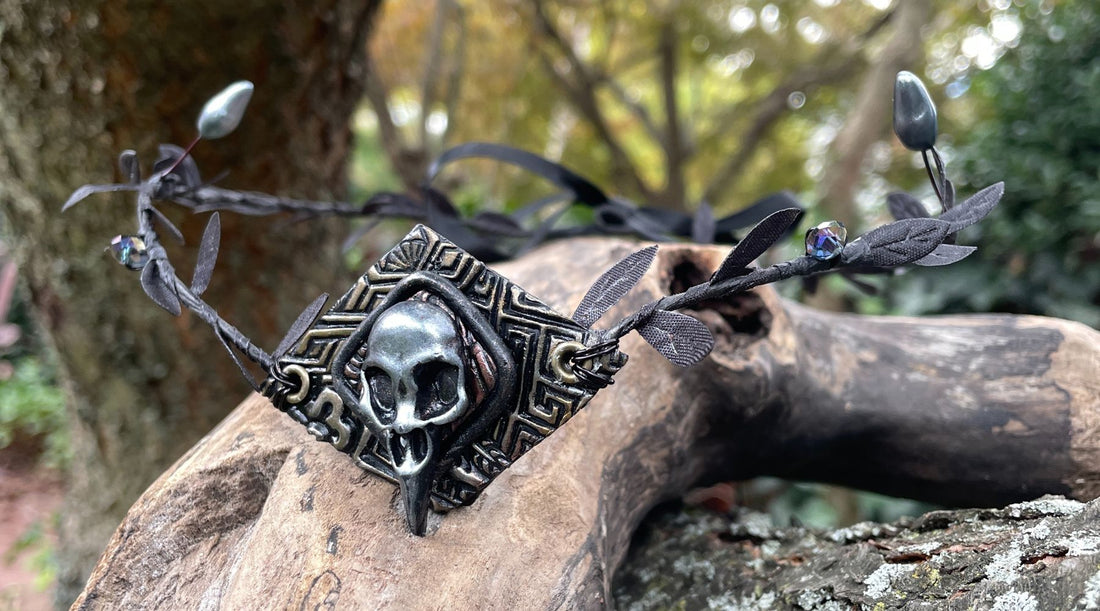 Silver raven skull diadem headpiece with black leaf ribbon and silver flower buds and black crystals on a tree branch.