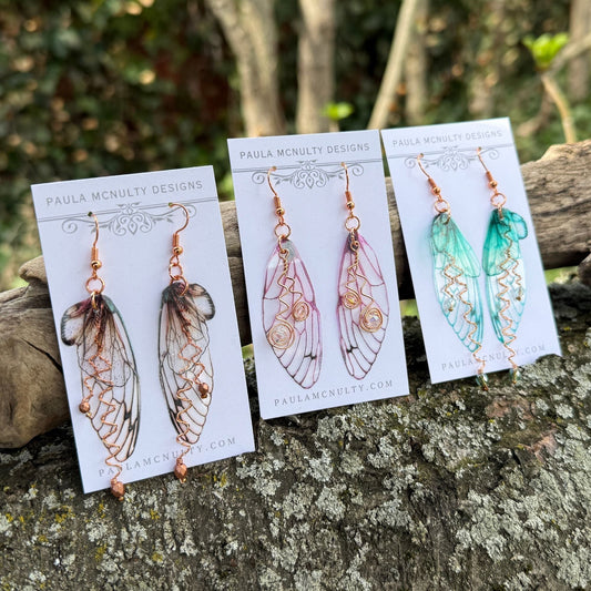 3 pairs of butterfly wing earrings on white cards lined up on a tree branch