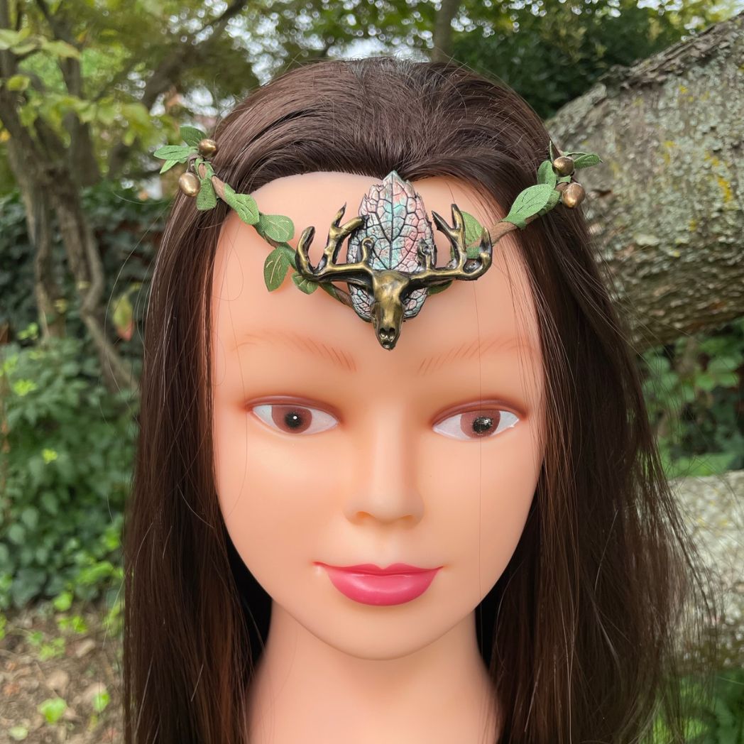 A wire crown with green leaves and a polymer clay leaf and elk focal on a model.