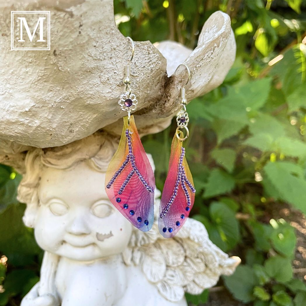 Colorful rainbow sheer fabric with beading and blue crystals. A flower bead with a crystal connects the wings to the ear wires.