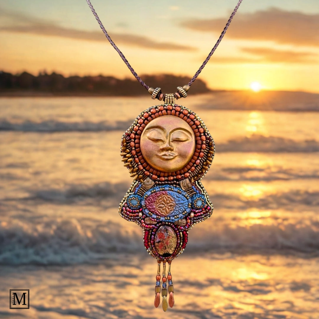 Decorative necklace with a sun design against a sunset beach backdrop
