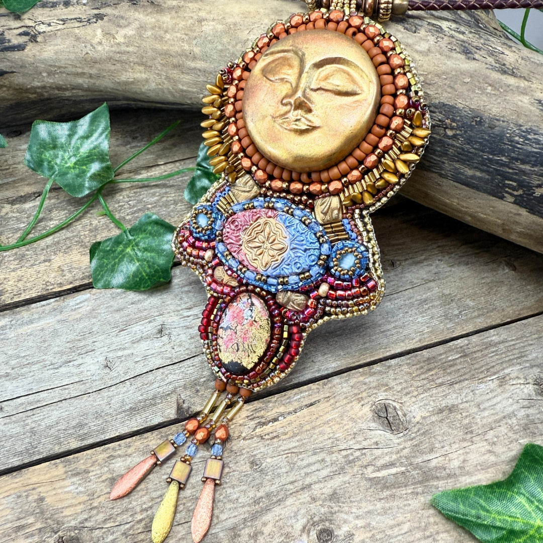 Decorative brooch with sun design on a wooden surface with leaves