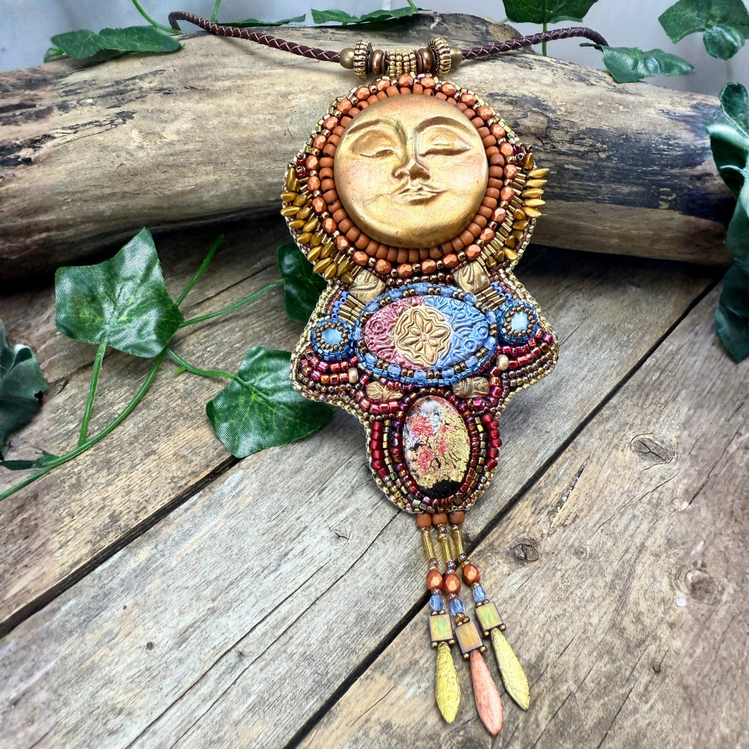 Colorful beaded necklace with sun design on a wooden surface with leaves.