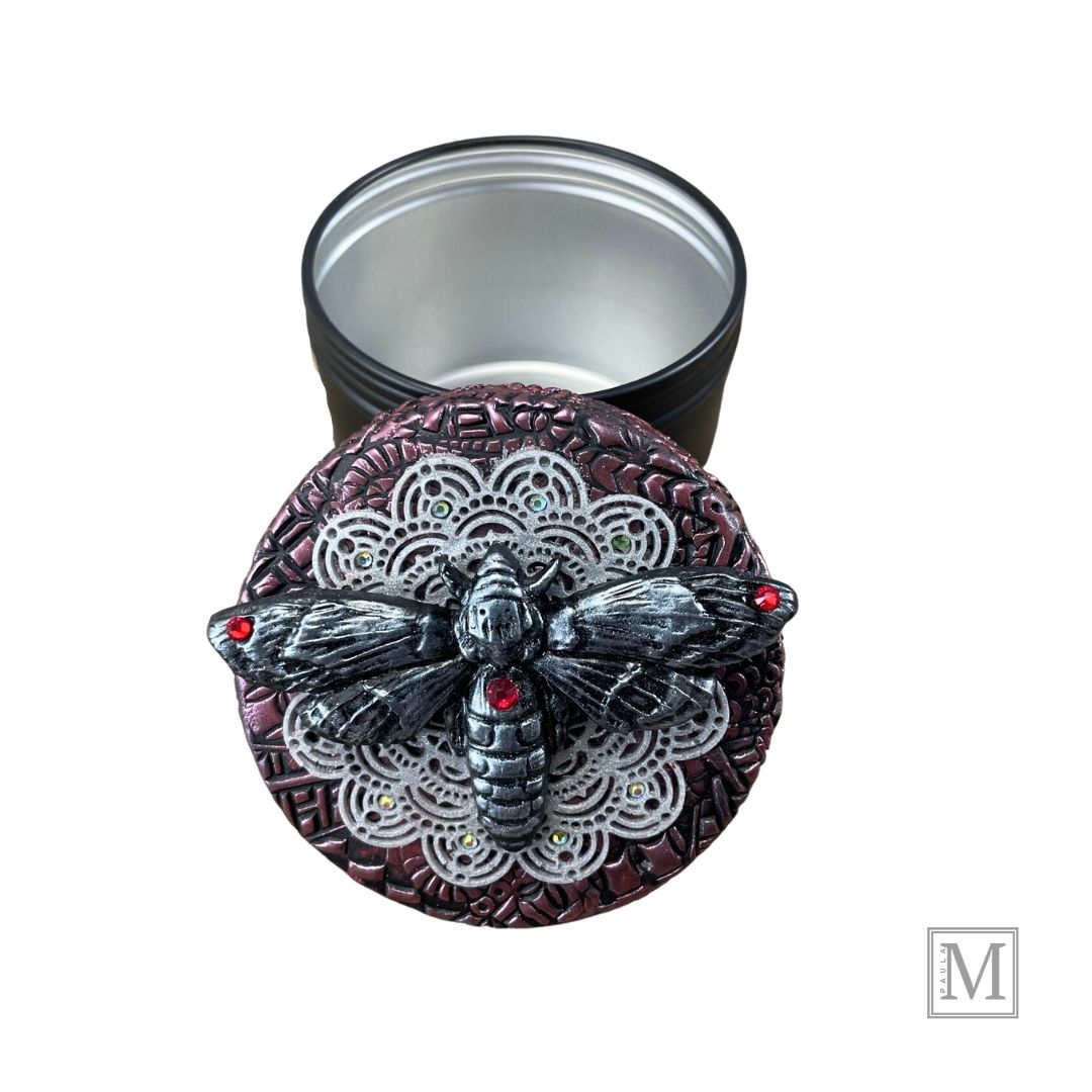 4oz black aluminum storage tin with handcrafted polymer clay purple textured lid with lace detail. with a hawkmoth with red crystal on abdomen.