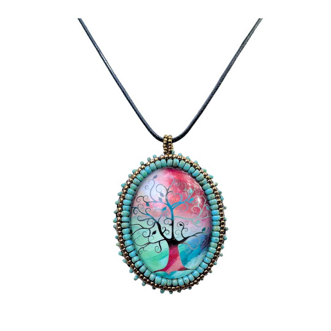 Silhoutte whimsical tree with red, blue and green background in an oval pendant with glass cabochon and green and gold seed bead edging.
