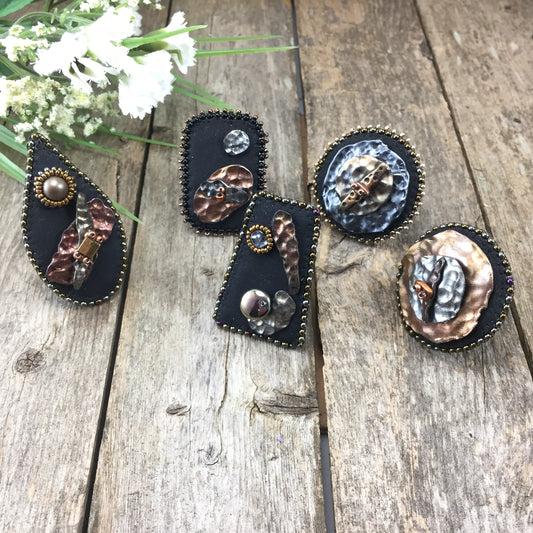 Collection of statement rings with abstract hammered copper and silver clay with dark gold beaded edge