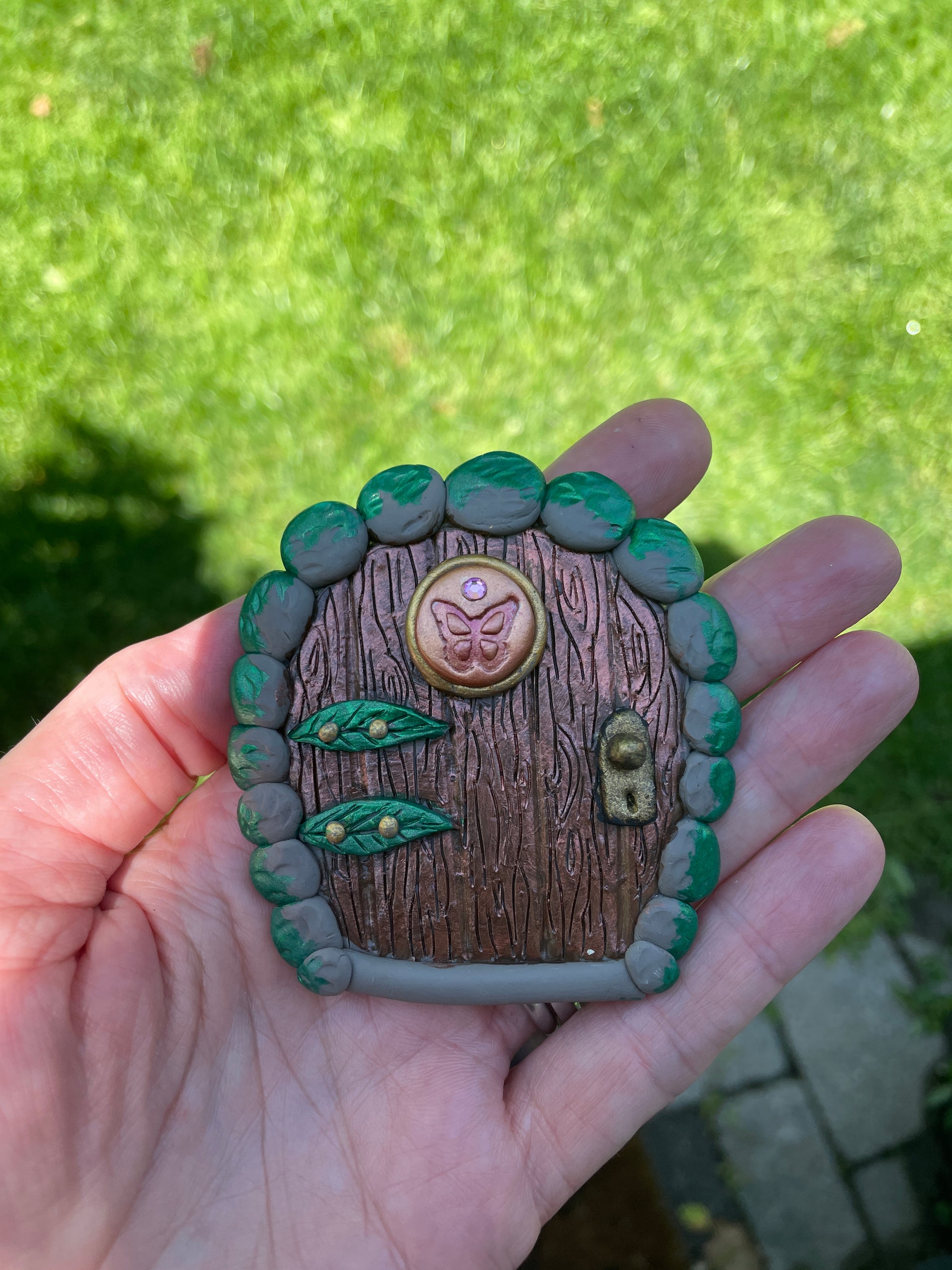 small butterfly fairy door ornament with butterfly and leaf details held in a hand.