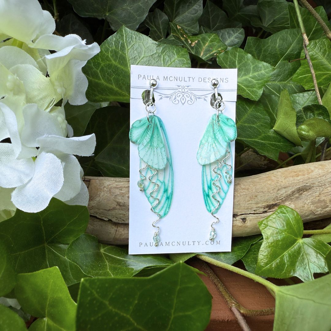 Handmade mint green clip-on earrings with delicate butterfly wings and twisted metal detail.