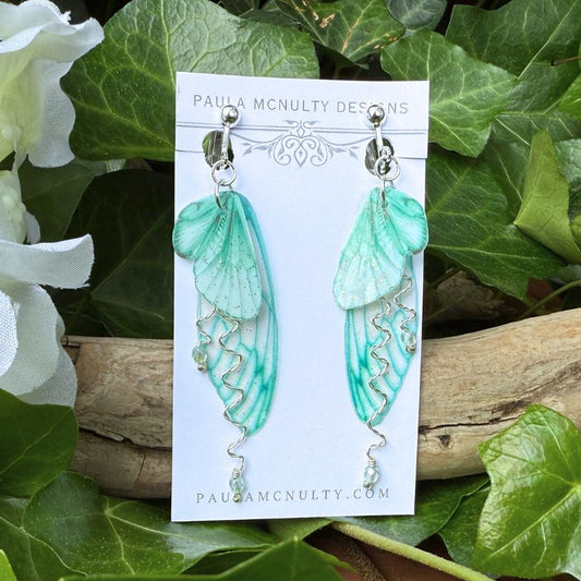 Handmade mint green clip-on earrings with delicate butterfly wings and twisted metal detail.