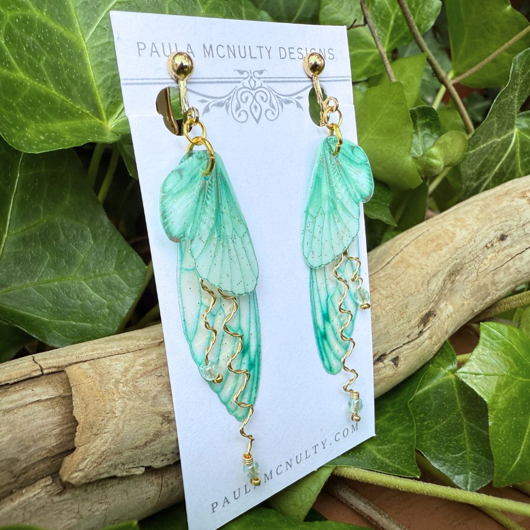 Close-up view of comfort pad clip-on backing on mint green butterfly earrings.