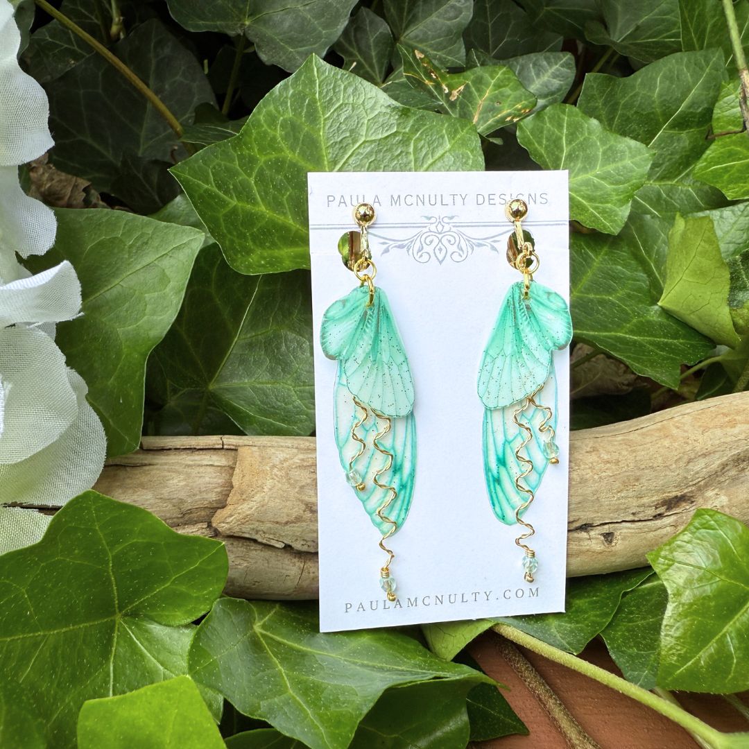 Gold finish mint green fairy wing earrings displayed on jewelry card from Paula McNulty Designs.