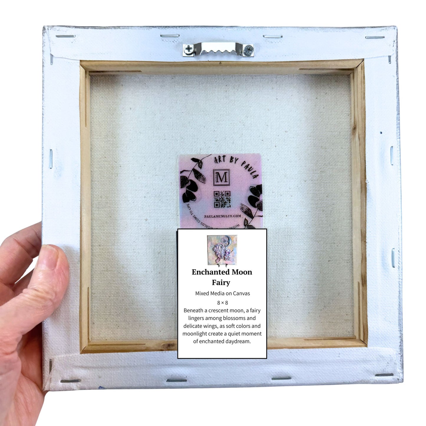 Hand holding a framed artwork with a label on a white background