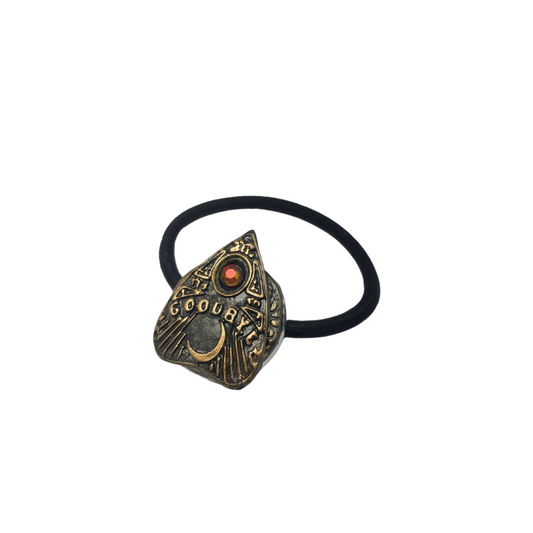 Ouija board planchette hair tie with  red crystal and the word 'goodbye' in gold lettering on a white background