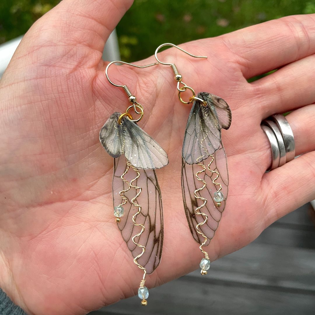 olive green fairy earrings held in a hand.
