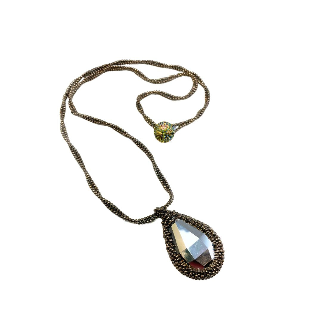 Back of large beaded teardrop shaped rainbow crystal necklace with twisted beaded chain with an iridescent button closure.