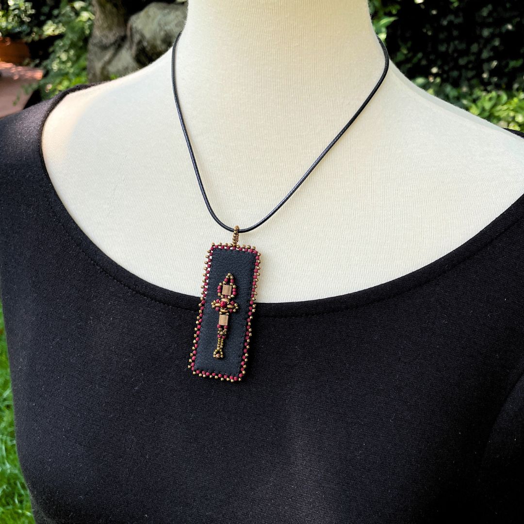  red and gold Renaissance beaded faux leather rectangle pendant with beaded edge on a model.