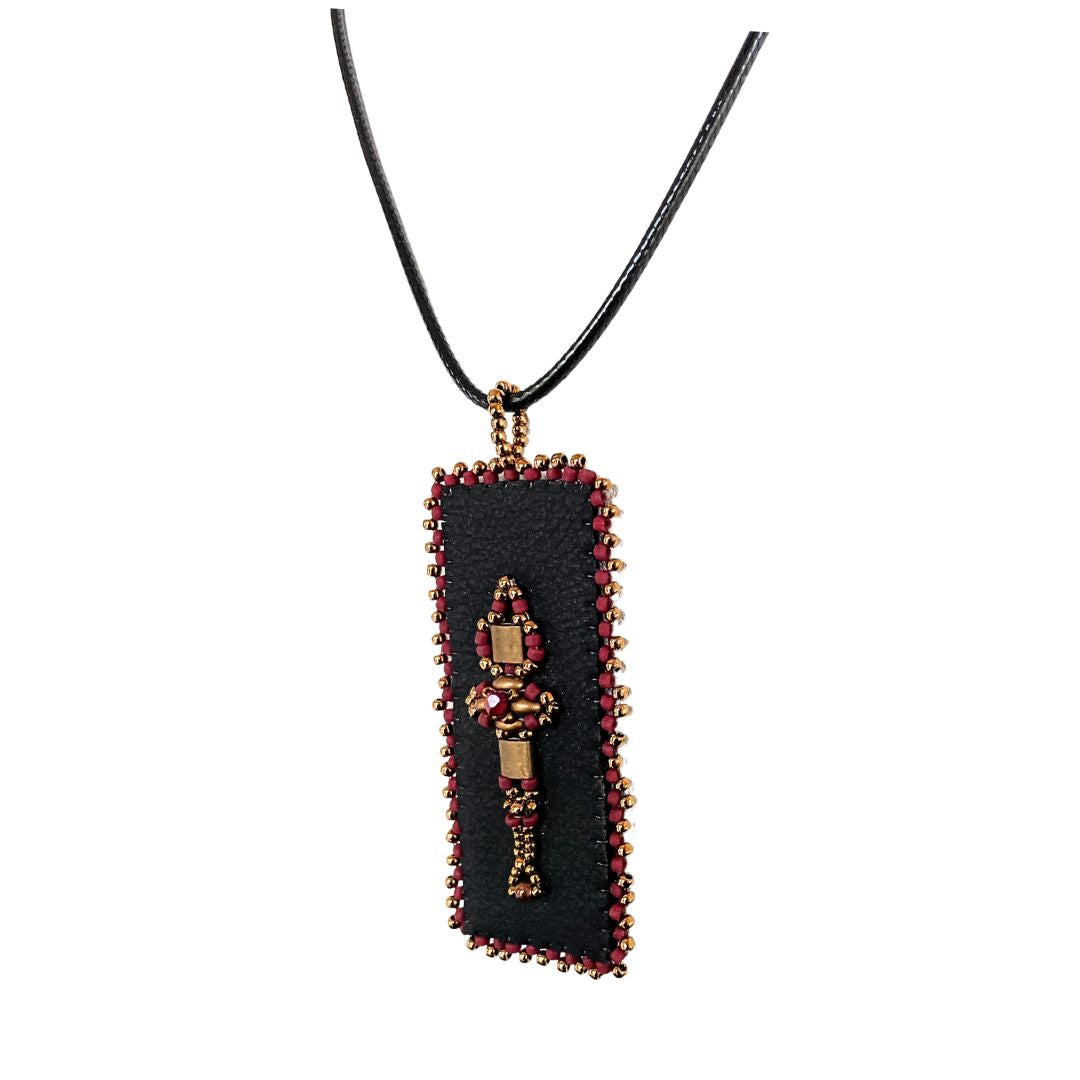 Side view of red and gold Beaded faux leather rectangle pendant with beaded edge.