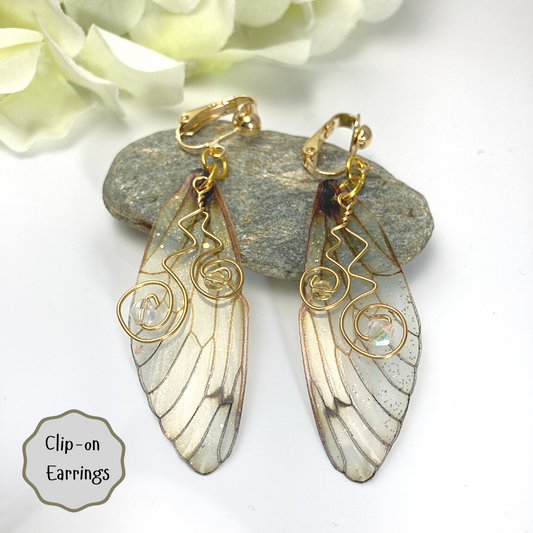 yellow butterfly wing clip on earrings  leaning on a rock with a  yellow flower in the background
