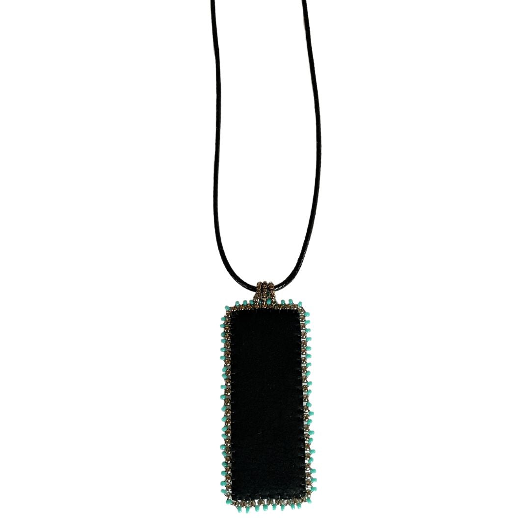 Back of Medieval Jewelry black faux leather rectangle pendant with turquoise and gold beading with black cord necklace.