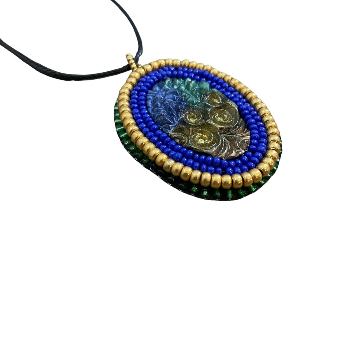 Blue green and gold zentangle pattern pendant with blue and gold beaded edge.