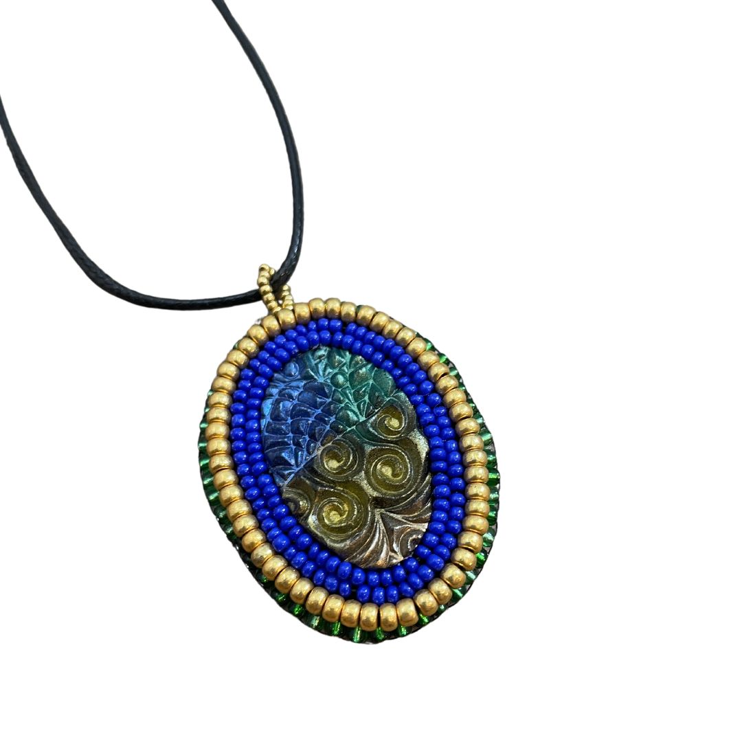 Blue green and gold zentangle pattern pendant with blue and gold beaded edge.