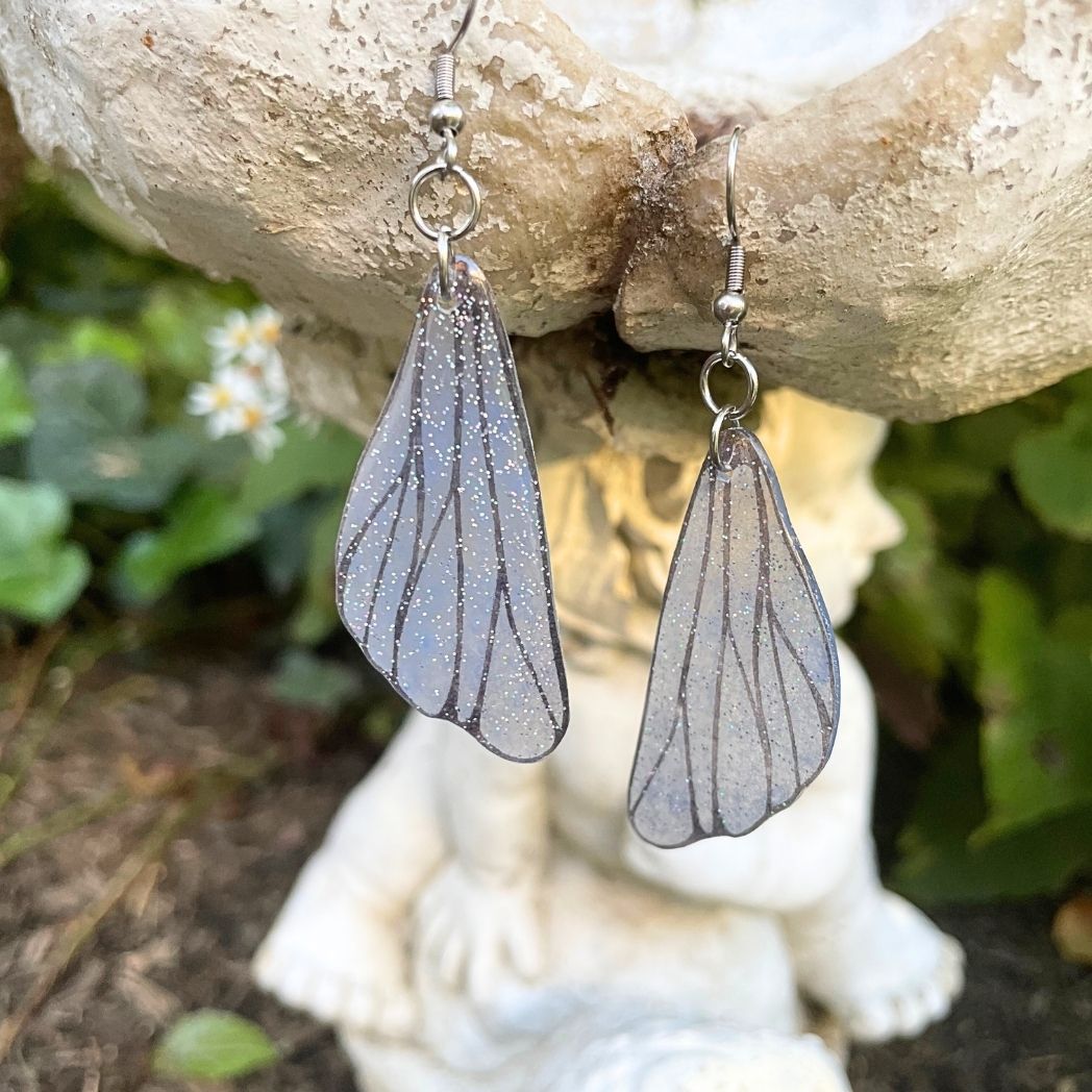 gray  small wing earrings hanging on a garden ornment.