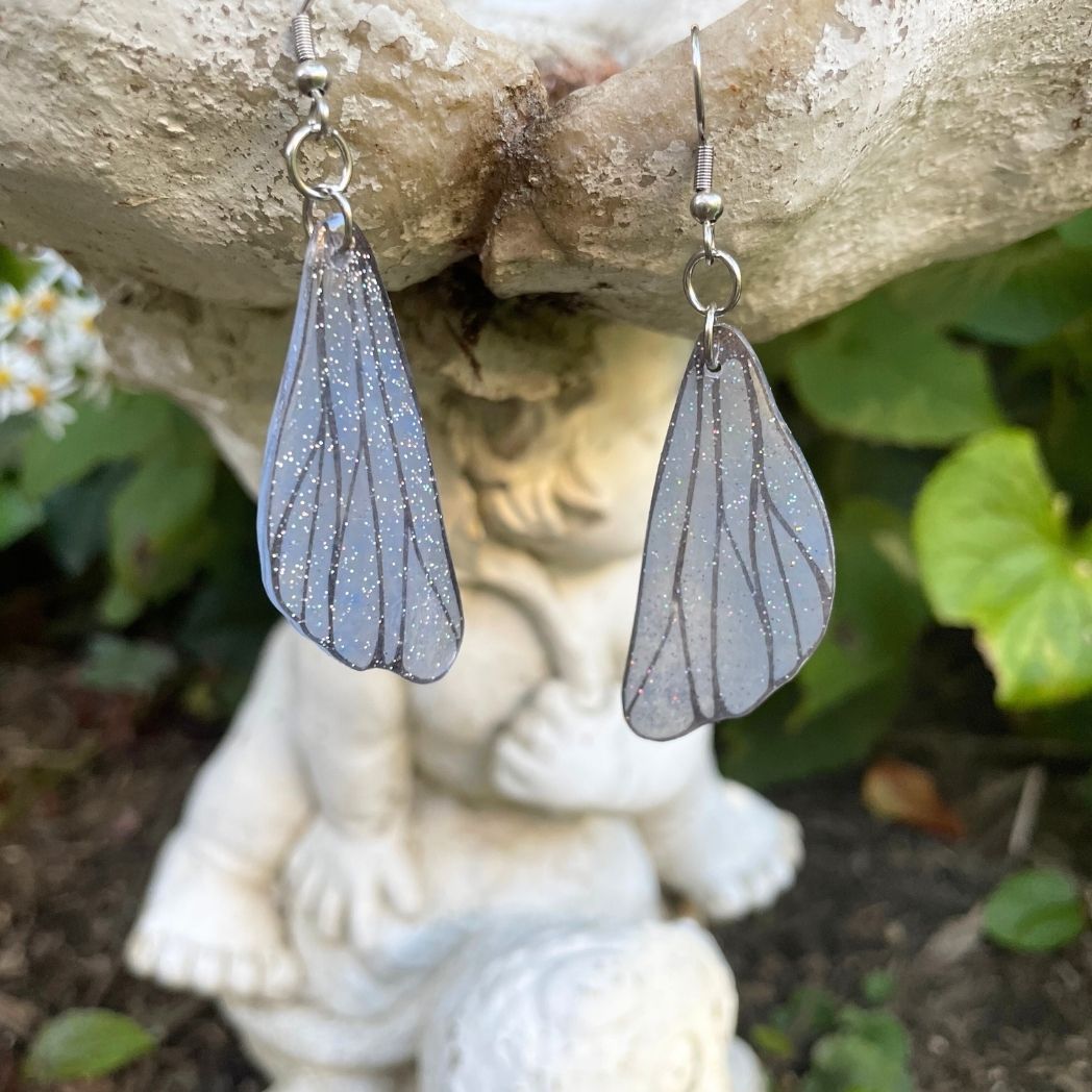 gray small wing earrings hanging on a garden ornment.