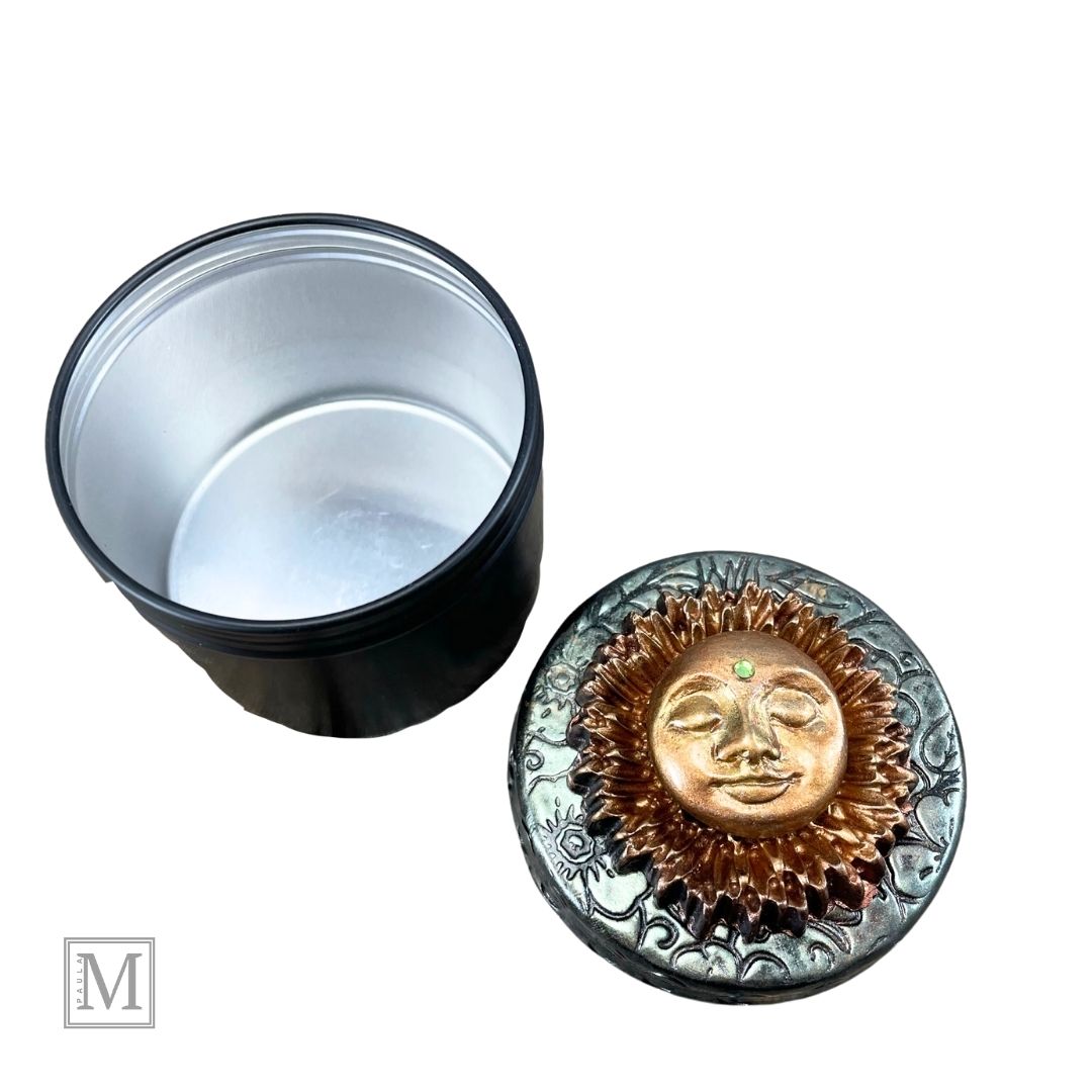 Black storage tin with decorative polymer clay lid with gold sun face design.