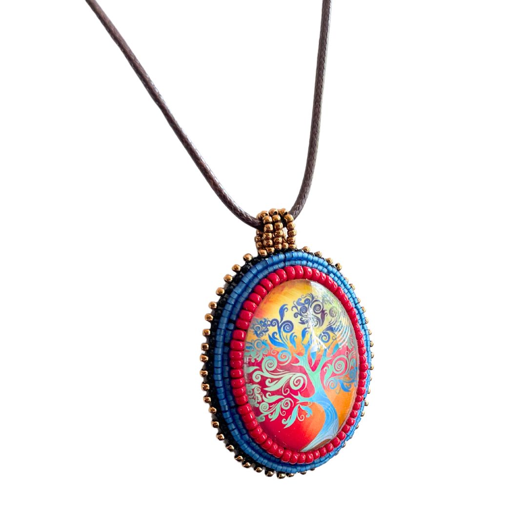Ovsl pendant with swirly whimsical blue tree with gold and red sunset with blue, red and black glass seed bead edging with brown cord necklace