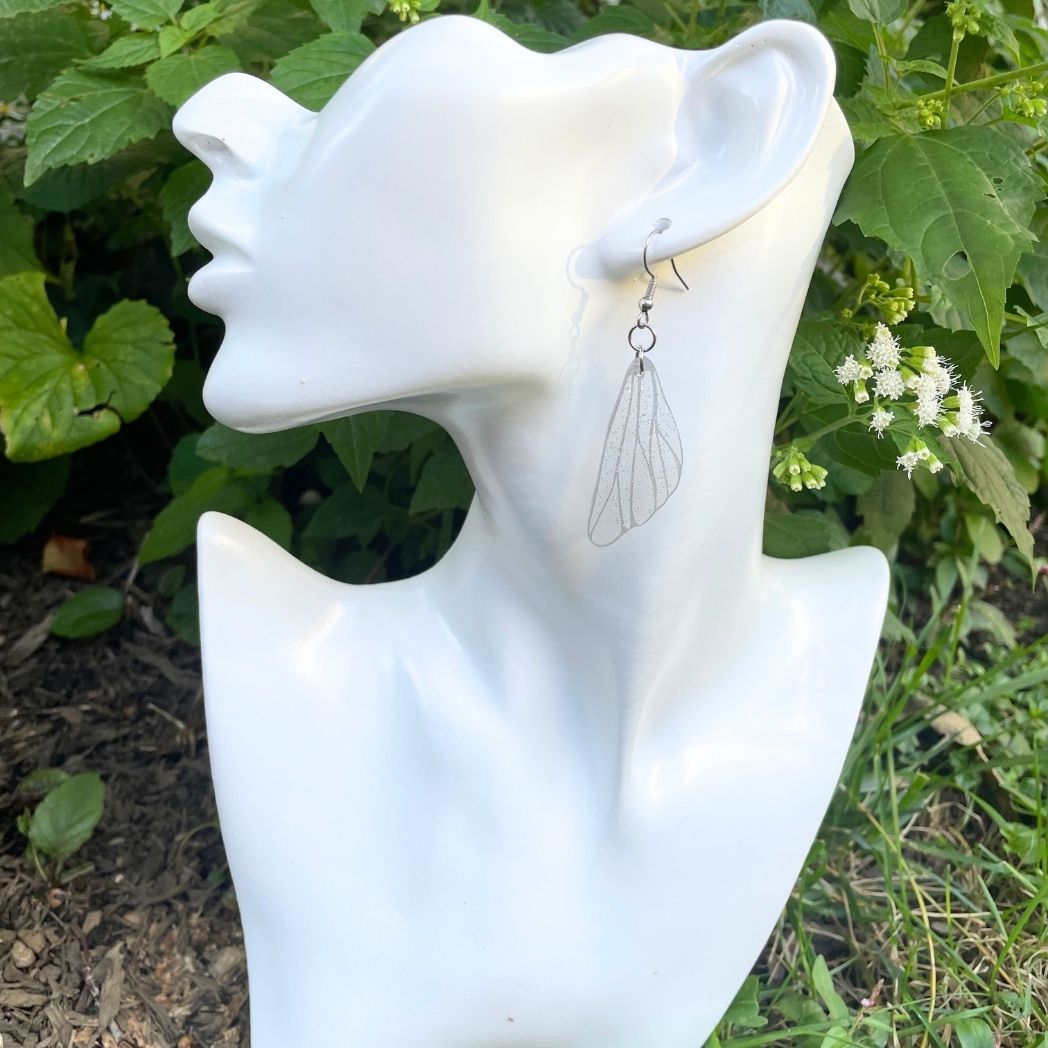 Clear silver glittered wing earring on an earring model bust.