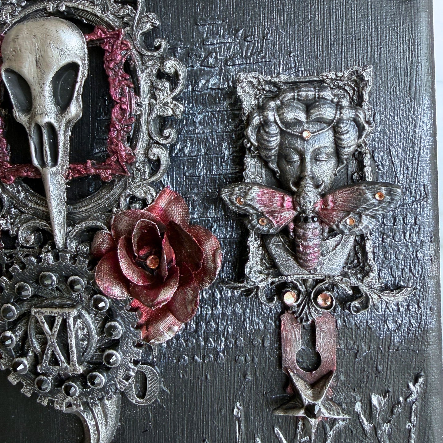 Decorative wall piece with skull, rose, and butterfly on a textured dark background