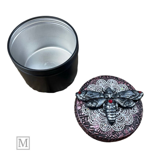 4oz black aluminum storage tin with handcrafted polymer clay purple textured  lid with lace detail. with a hawkmoth  with red crystal on abdomen.