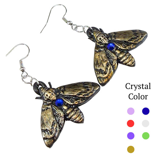 A pair of moth-shaped dangling earrings with an antiqued bronze finish and a small blue crystal accent, shown on a white background with a 'Crystal Color' color options chart on the right.
