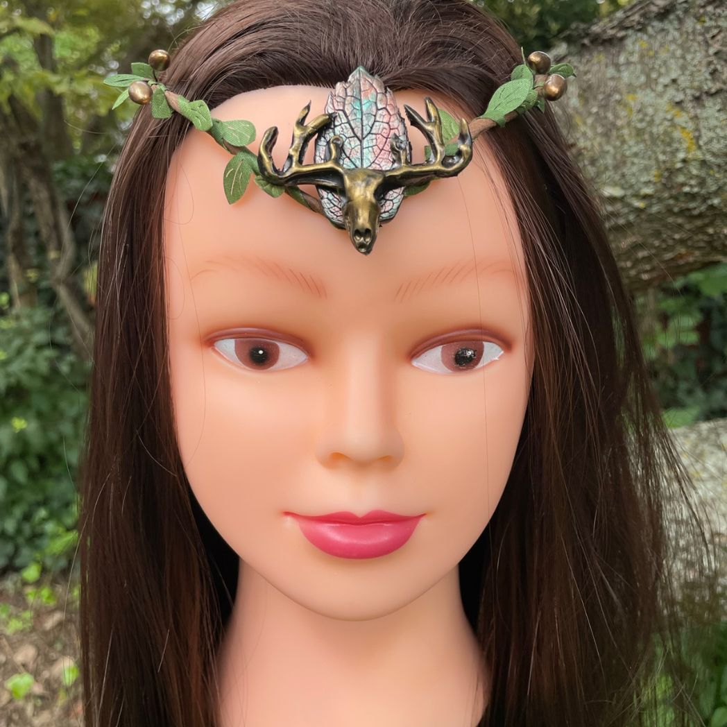 A wire crown with green leaves and a polymer clay leaf and elk focal on a model.