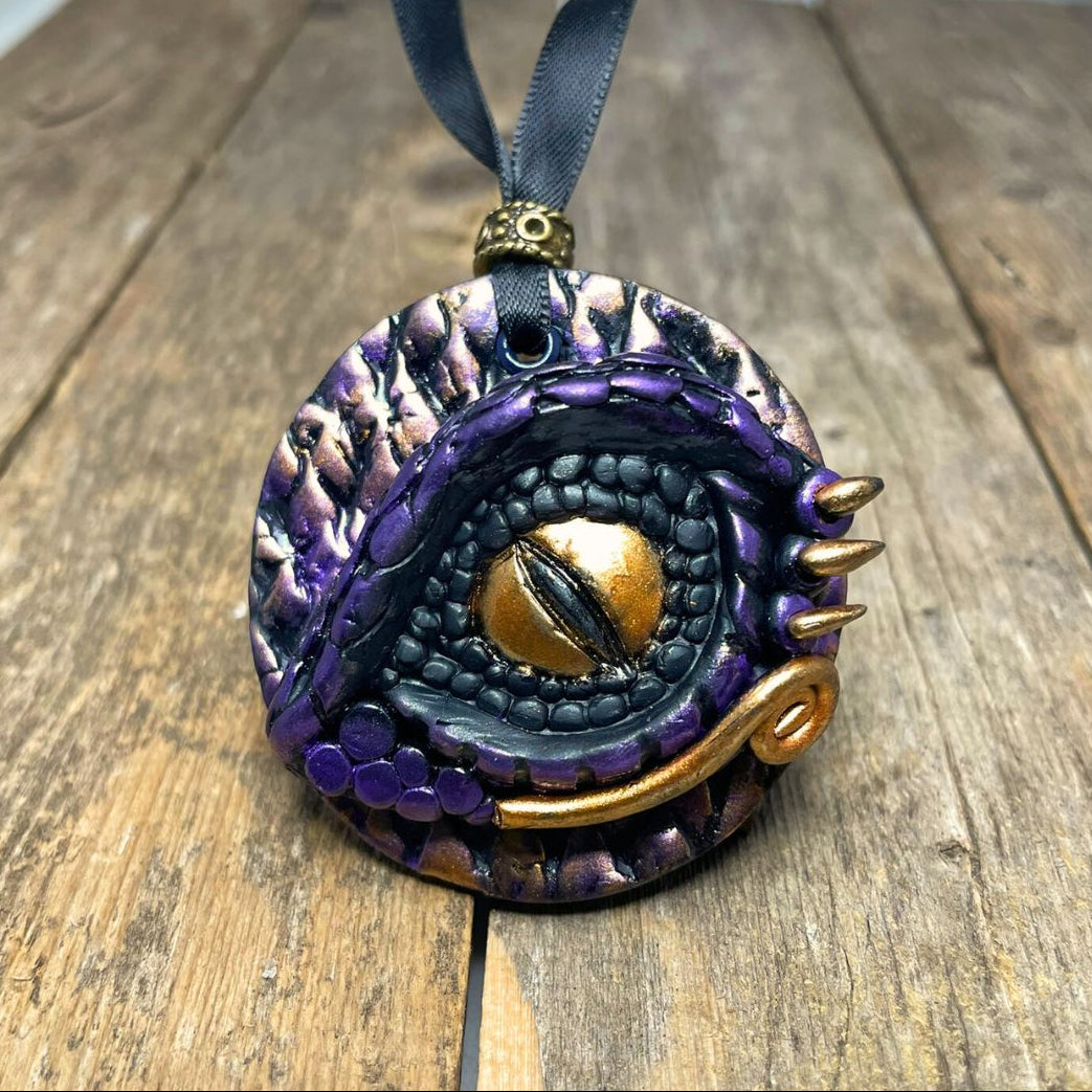 Decorative purple and gold pendant on a wooden surface