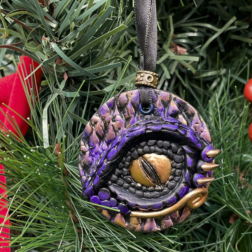 Decorative ornament with a purple and gold design on a green Christmas tree.